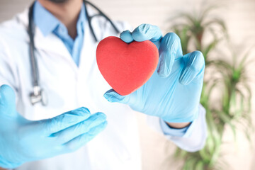 doctor hand in latex gloves holding red heart close up