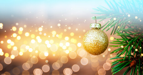 Christmas Fir tree with Golden Bauble and defocused lights in the background. Copy Space