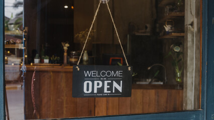 Welcome we're open vintage black and white retro sign on a coffee glass door cafe after coronavirus lockdown quarantine. Owner small business, food and drink, business reopen again concept.