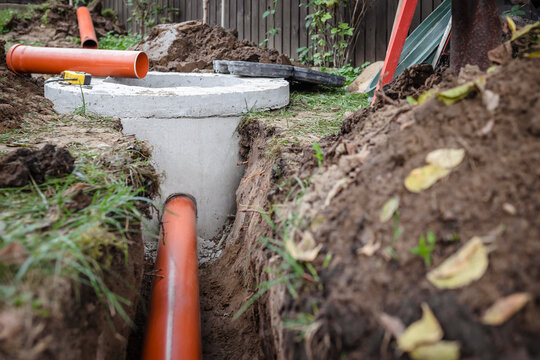 Septic Tank Installing in Dug Hole. Installation Concrete Sewer Rings Septic Well and Laying Pipes for Sewage Waste Water.
