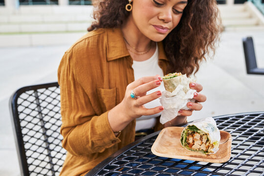 woman eats wrap at outdoor table