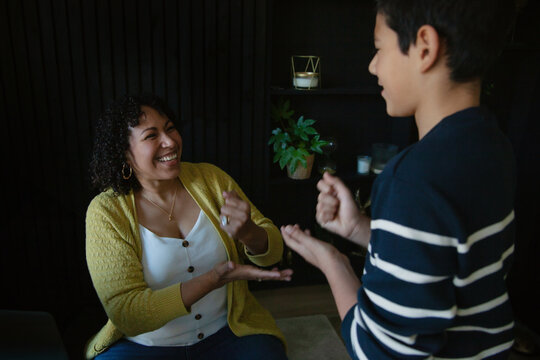 Mother and son playing rock paper scissors in living room and laughing
