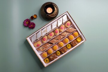 Indian assorted Diwali sweets or mithai box with diya and flowers. Festive gift idea. Kaju katli,...