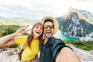 Foto op Aluminium Happy couple taking selfie pic with smart mobile phone on top of the mountain - Young hikers climbing the cliff - Sport, technology and travel life style concept © Davide Angelini