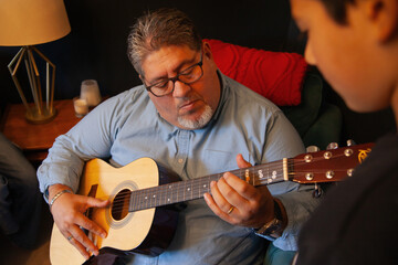 Obraz premium Father playing the guitar with his son in the living room