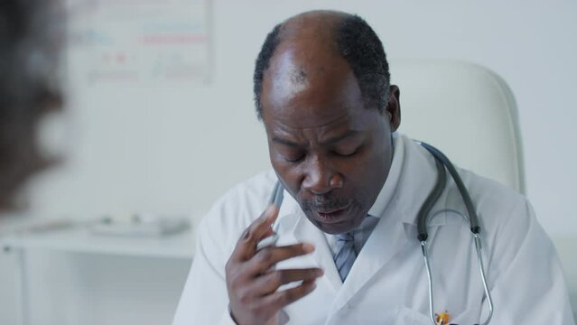 Close up of male African American doctor with stethoscope speaking with patient about complaints and asking clarifying questions in hospital