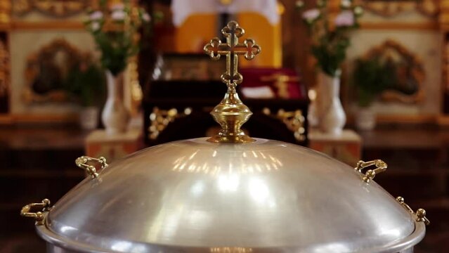 Aluminium church font, large bowl, with golden cross and saint water for the baptism of babies in Orthodox Church temple, Christening ceremony. Concept of rituals, sacraments of the Christian religion