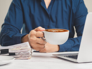 Businesswoman holding a cup of coffee while sitting at the table