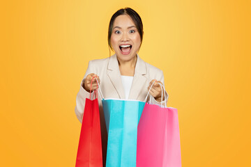 Surprised glad young japanese lady shopaholic open colorful bags, with purchases enjoy shopping