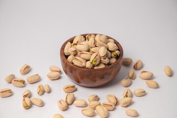 Pistachios or salt Pista on white bowl with white background, Pistachios or salt Pista scattered on the white background in a black bowl or wooden bowl. A raw salted pistachios consumed for food