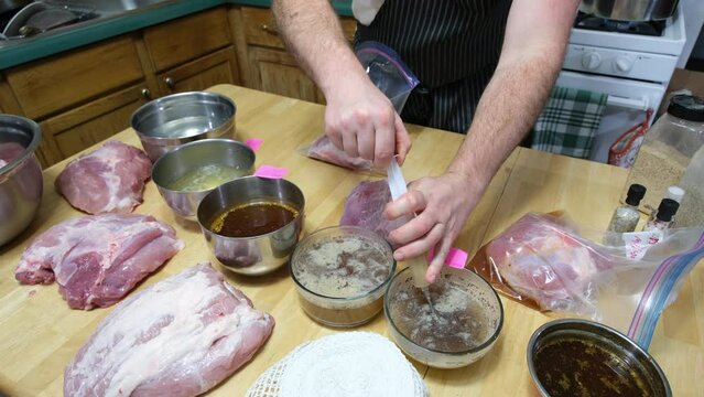 Injecting black pepper and salt solution around chunk of pork meat packed in plastic zip bags for marinating meat and preparing for smoking.to make home made ham.