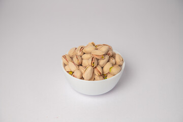 Pistachios or salt Pista on white bowl with white background, Pistachios or salt Pista scattered on the white background in a black bowl or wooden bowl. A raw salted pistachios consumed for food