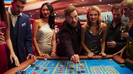 Casino Enthusiasts Making Calculated Bets at a Roulette Table. International Crowd of Young Beautiful and Handsome Adults Enjoying the Night Out Activity. Lucky Gamblers Grabbing the Jackpot