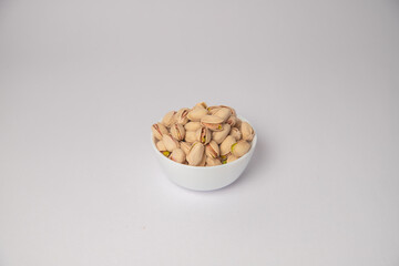 Pistachios or salt Pista on white bowl with white background, Pistachios or salt Pista scattered on...