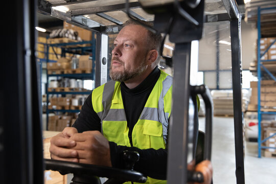 Portrait of employee in distribution warehouse driving a forklift truck