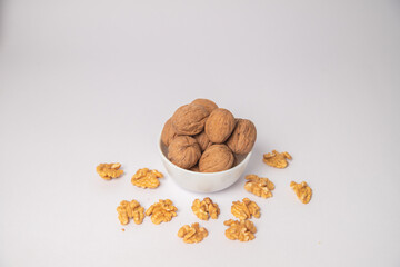 Walnut or walnuts with shell on white bowl with white background, Walnut or walnuts with shell scattered on the white background in a black bowl or wooden bowl. walnut from Juglans