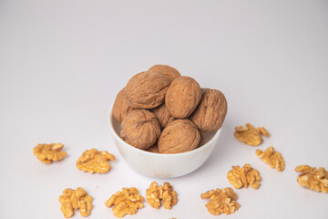 Walnut or walnuts with shell on white bowl with white background, Walnut or walnuts with shell scattered on the white background in a black bowl or wooden bowl. walnut from Juglans
