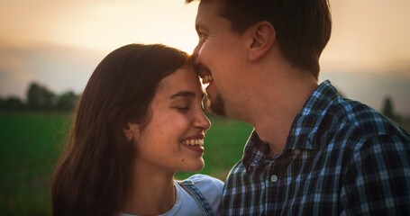 Young Beautiful Couple Hugging and Kissing Outdoors on a Countryside Road with Scenic Green Fields. Relationship Concept with Loving Partners Enjoy Spending Time and Traveling Together
