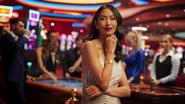 Beautiful Young Asian Woman, Wearing an Elegant Silver Dress, Standing in a Modeling Pose in a Glamorous Atmosphere of a Casino, Surrounded by Active Gamblers in the Background. Flare Visual Effect