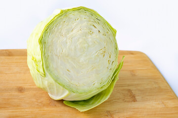 A head of cabbage cut in half on a wooden kitchen board. Health benefits of vegetables and healthy eating.