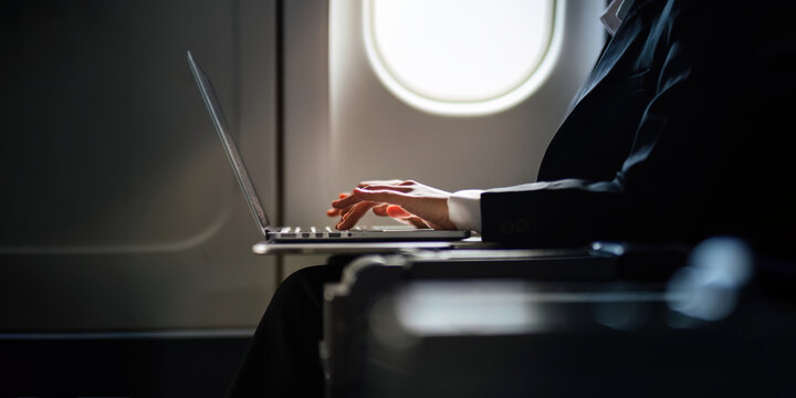 Successful Asian business woman, Business woman working in airplane cabin during flight on laptop computer