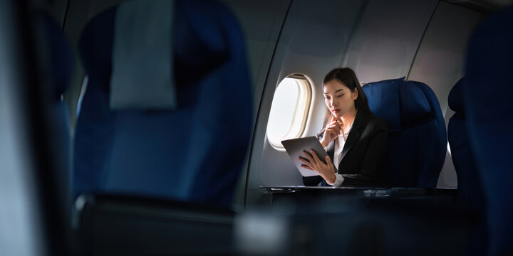 Successful Asian business woman, Business woman working in airplane cabin during flight on tablet