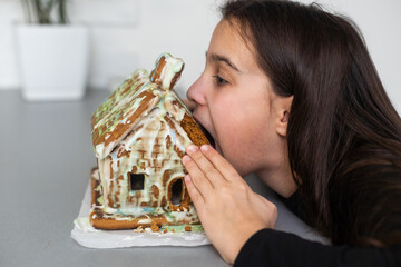 A teenage girl is eating a gingerbread house