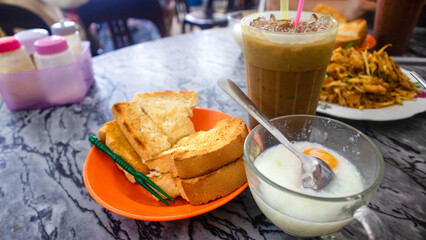 Common oriental breakfast set in Malaysia consisting of coffee, nasi lemak, toast bread and half-boiled egg, Breakfast toast set with coffee and toast bread with butter and kaya, a typical breakfast 