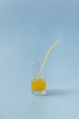 Summer fresh drink in glass with yellow tube straw on bright blue background. Minimal refreshment concept idea.