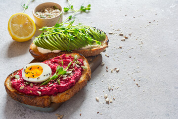 Whole grain toast with cream cheese, avocado, beetroot hummus, seeds, egg and microgreens (sprouted pea sprouts) on a light gray background. Healthy food concept. - obrazy, fototapety, plakaty