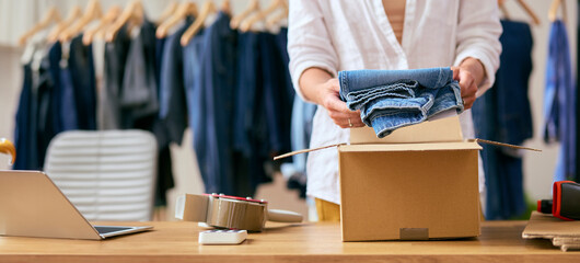 Close Up Of Woman Running Online Fashion Business Packing Order Of Denim Jeans Up Into Box