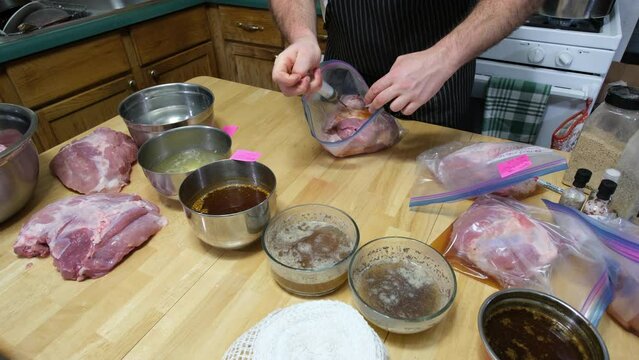 Injecting barbecue flavor solution around chunk of pork meat packed in plastic zip bags for marinating meat and preparing for smoking.to make home made ham.