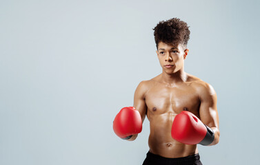 boxer guy with red gloves in fighting stance, gray backdrop