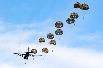 Military parachutist paratroopers parachute jumping out of an air force plane.