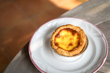 Portuguese egg tart on a white plate. Delicious pastry.