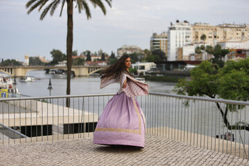 Obraz premium Young woman, Hispanic, beautiful, brunette, with an elegant vintage violet dress , giving funny twists to make her dress fly. Concept of beauty, fashion, trend, elegance, antique.