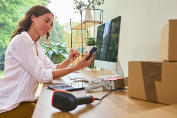 Woman Running Online Business From Home Working At Computer Using Mobile Phone