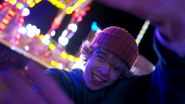 Creative teen man spinning camera performing contemporary dance at evening amusement park