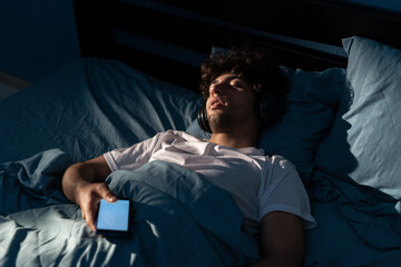 Arab man sleeping in bed at night with a smartphone suffers from social media addiction.