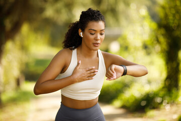woman runner checking smartwatch pausing and breathing in run outdoors - obrazy, fototapety, plakaty