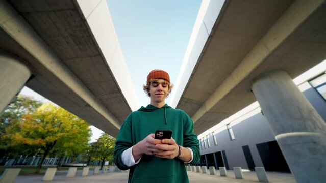 Smiling teen hipster texting smartphone at modern city closeup