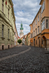 Narrow cobblestoned street in the downtown of Sopron, Hungary with the famour Fire Tower in the background 