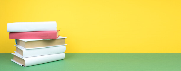 Books stacking. Open hardback books on wooden table and green background. Back to school. Copy space for ad text. Banner.