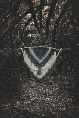 Panel of blue and white macrame on a decorative branch in nature