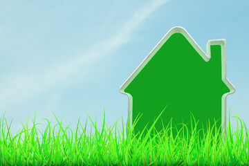 Green house model in green grass against blue sky background. Green house concept.
