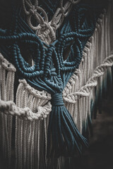 Panel of blue and white macrame on a decorative branch in nature