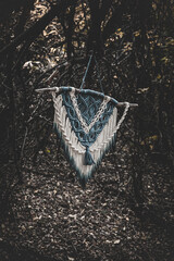 Panel of blue and white macrame on a decorative branch in nature