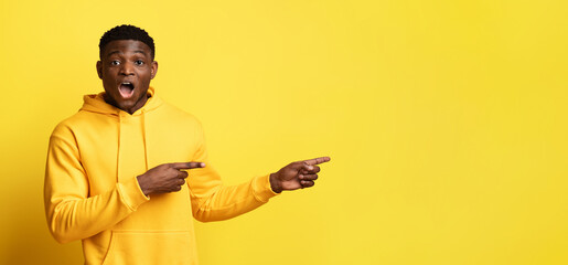 Amazed handsome black guy looking at copy space, panorama