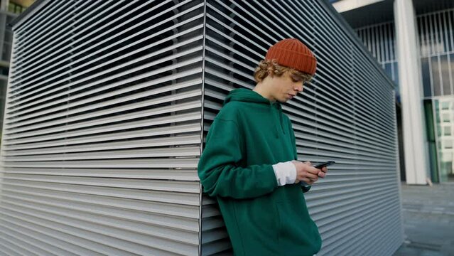 Contemporary teenager texting phone outdoors closeup
