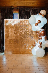 Photo zone with gold sequins and white and gold balloons. 